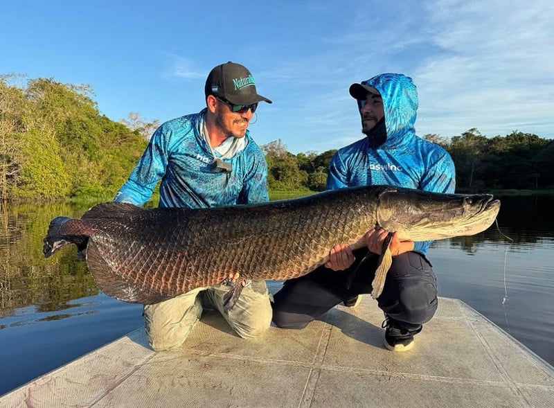 Two men holding a large arapaima on a dock in bolivia, fish with Arapaima Lodge